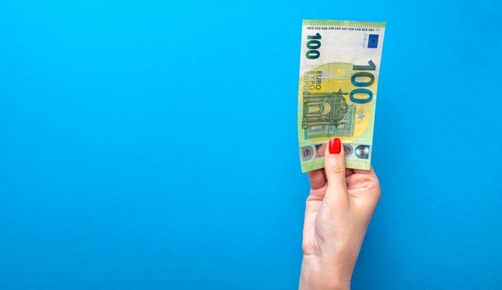 Una banconota da 100 euro in mano a una donna