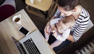 Mamma che lavora con il figlio tra le braccia