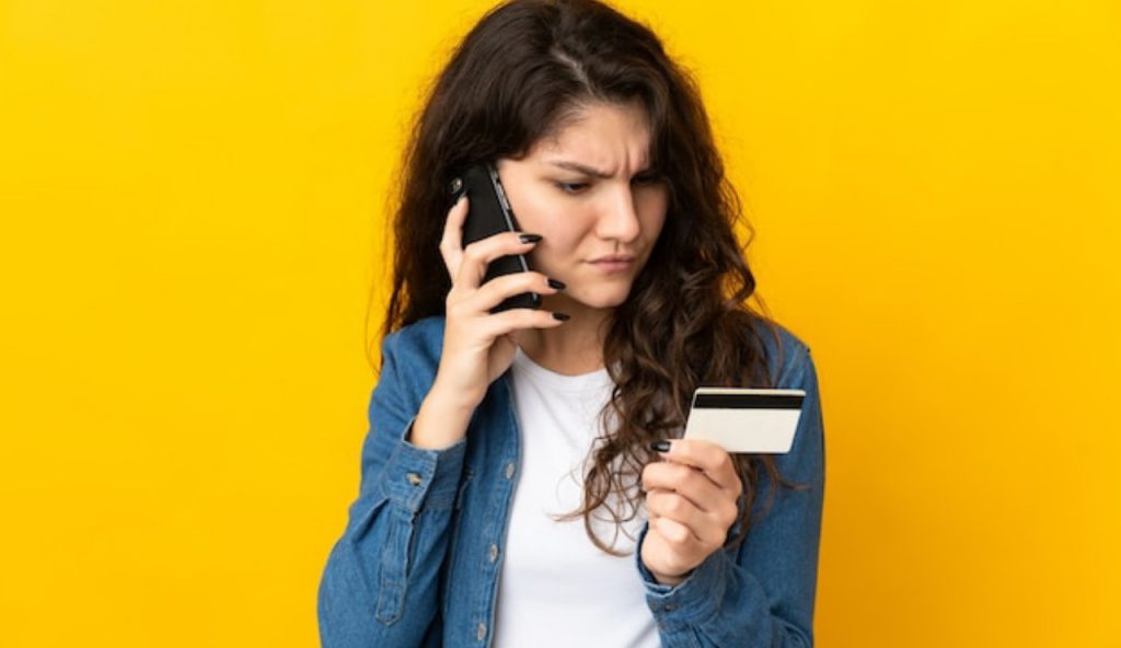 Una giovane ragazza guarda con perplessità una carta telefonica